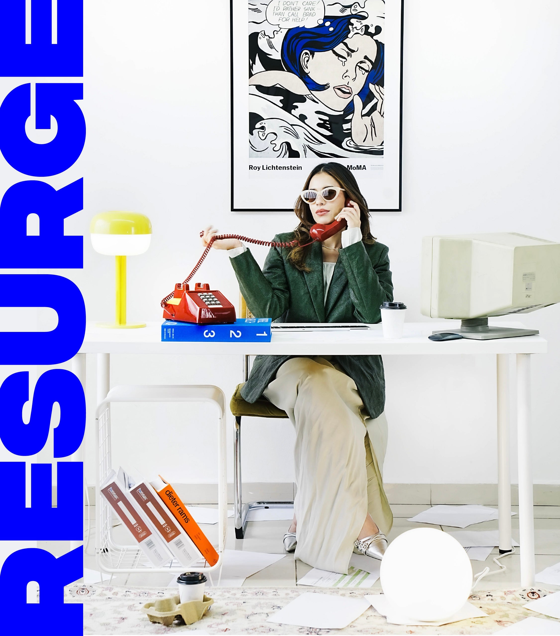 Mujer en oficina moderna con teléfono rojo vintage, computadora clásica y decoración minimalista, fusionando estilo retro y contemporáneo.